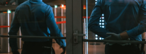 Two uniformed officers at a glass entrance door with hands clasped, the kind of controlled access point home security guards in South Florida staff